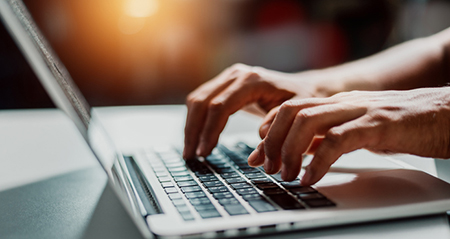 Hands typing on a laptop