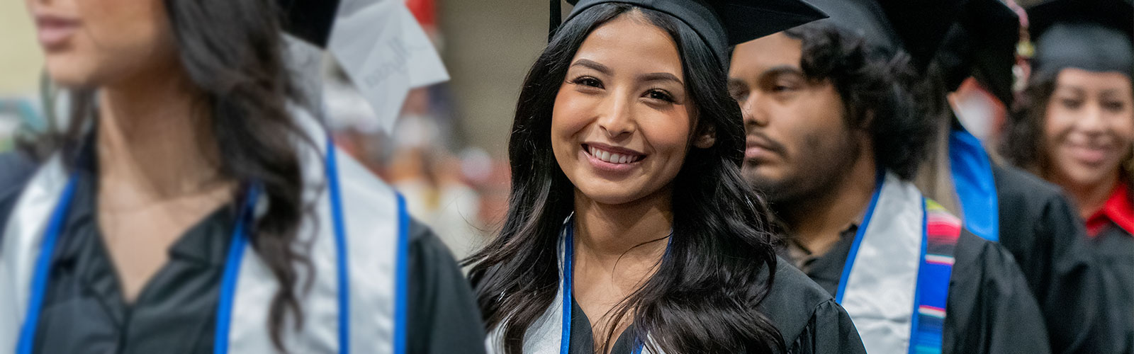 Students in line for graduation while one student smile at the camera