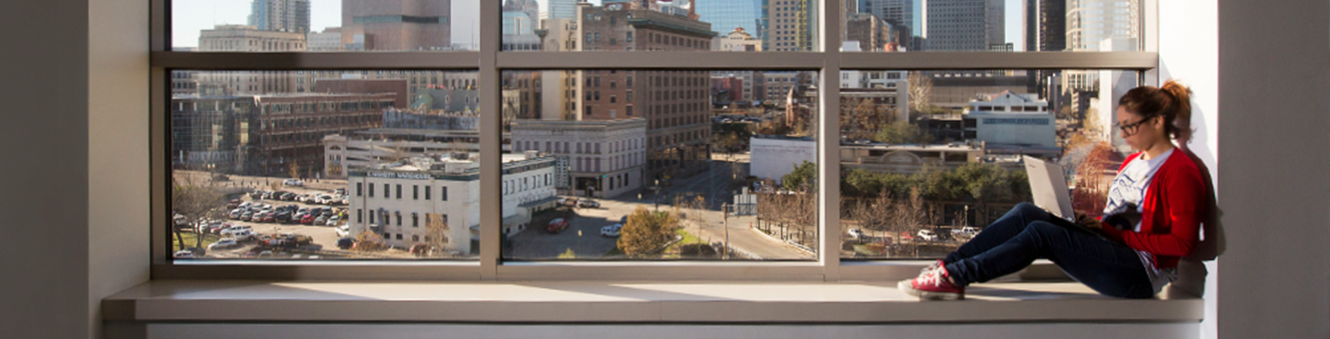 student sitting at window with view of downtown Houston