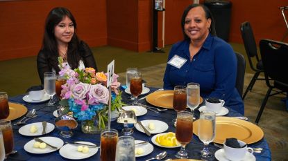 Donor scholar luncheon attendees smiling at a table while eating lunch