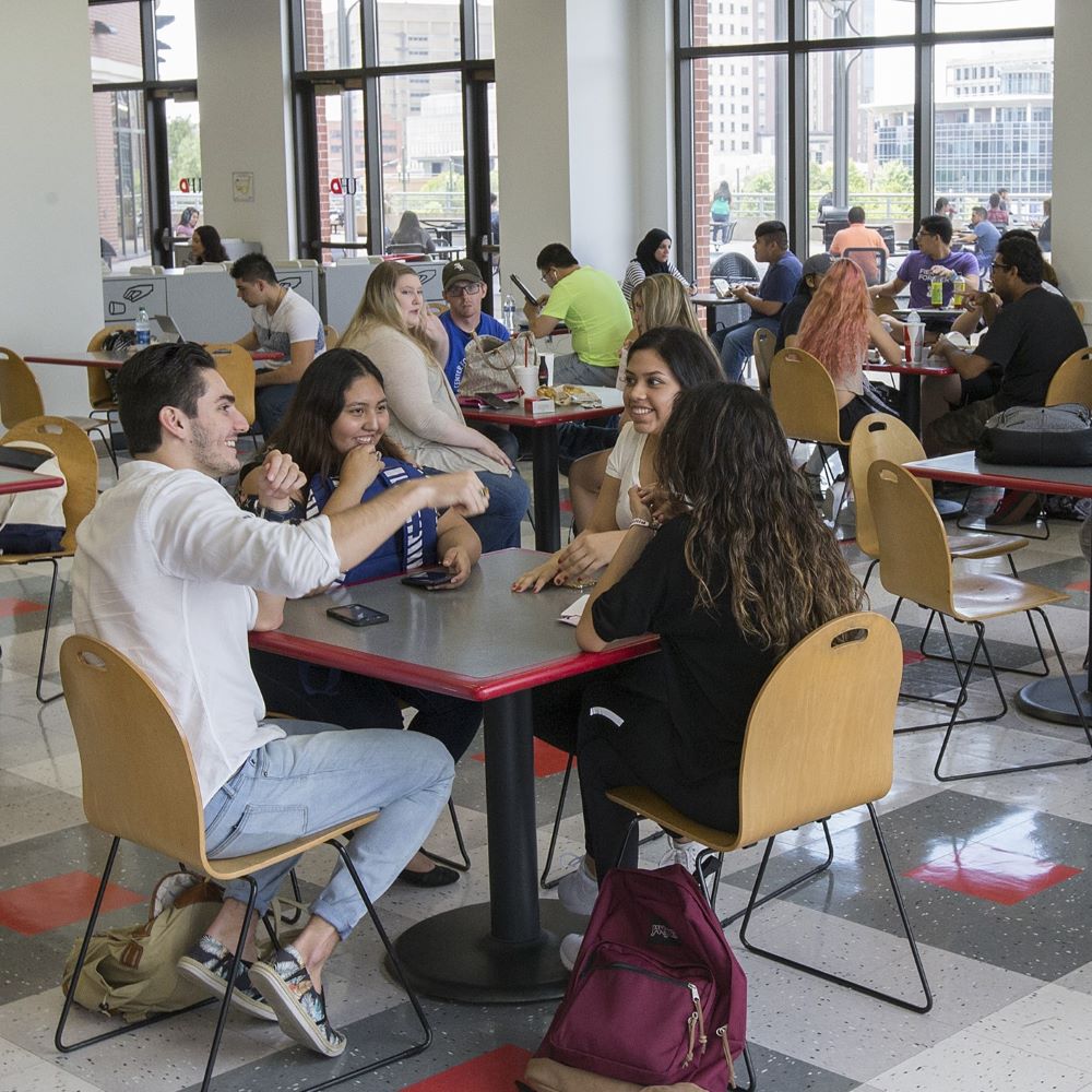 students sit at a table in UHD's food court