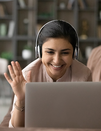 female student waving while viewing laptop