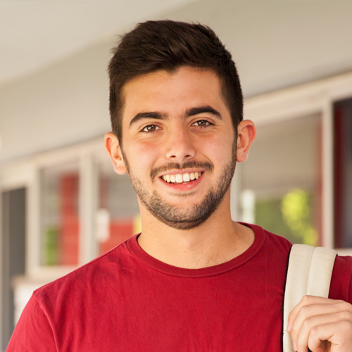 Smiling college student in a red t-shirt and carrying a Smiling college student in a red t-shirt and carrying a backpack