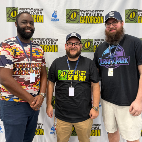 Tremaine Kwasikpui and José Vázquez and Jack Weisberger smile in front of a GatorCon backdrop at the university's first comic and cosplay convention